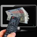 Immagine che illustra il concetto di tassa televisiva in bolletta con simboli di denaro e televisori.