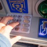 Bancomat con schermo che mostra segnalazioni automatiche per transazioni oltre mille euro.